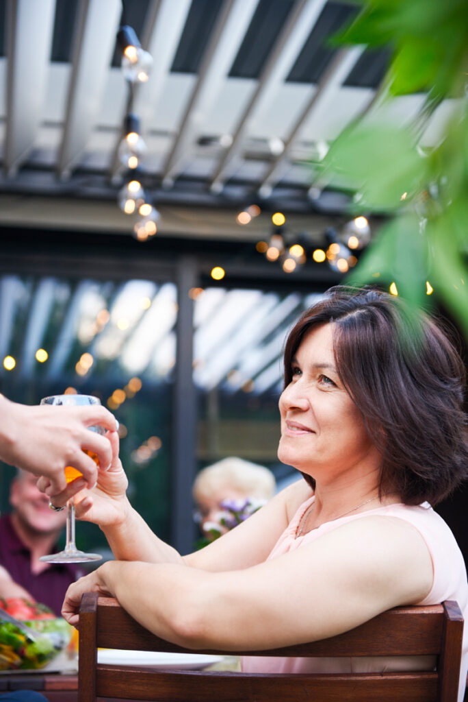 How Bellevue Families Are Creating All-Season Outdoor Spaces with Retractable Pergola Covers mature woman getting handed wine at family lunch o 2025 04 03 20 31 35 utc